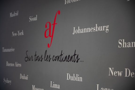 Text on a wall featuring "af" in red and various city names on a grey background.